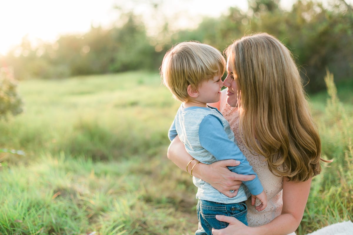 Mother hugging her young son in a green meadow