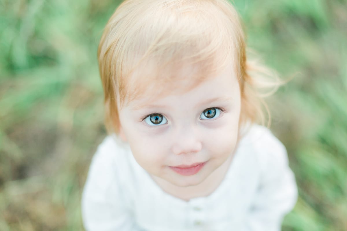 Close-up of a toddler girl with blue-green eyes looking up