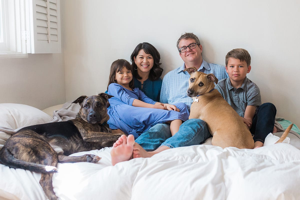 Rachel's family and their two rescue dogs relaxing on a bed