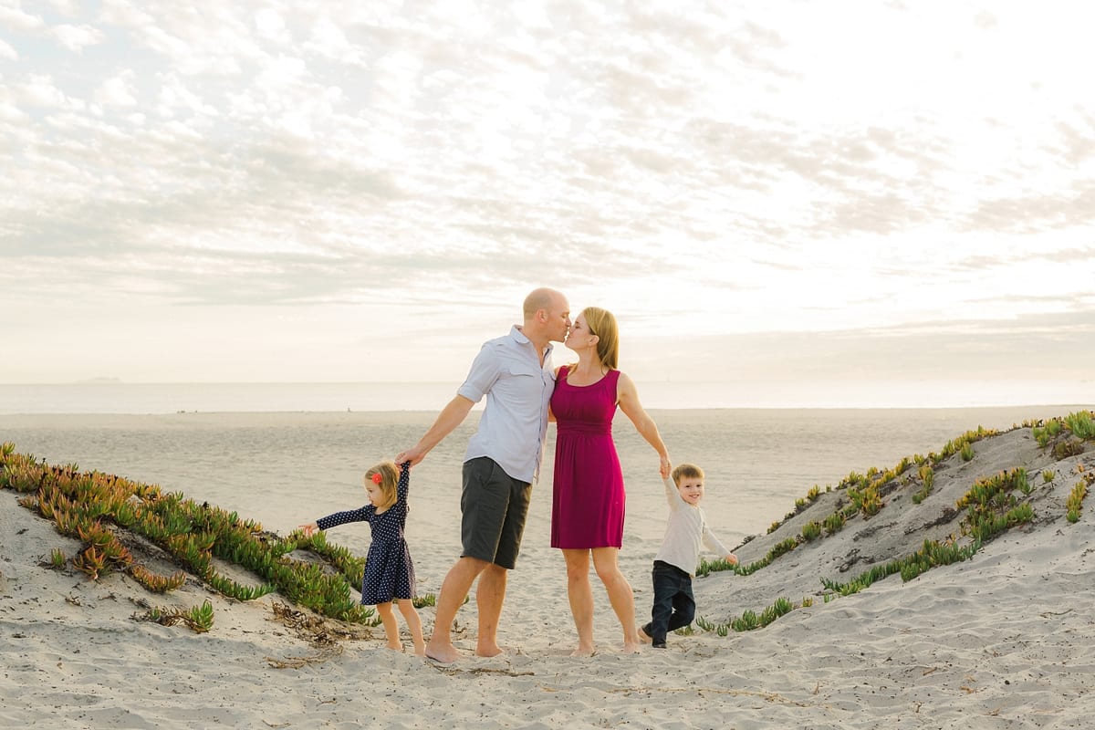 Parents kissing as their children play in the Coronado sand dunes