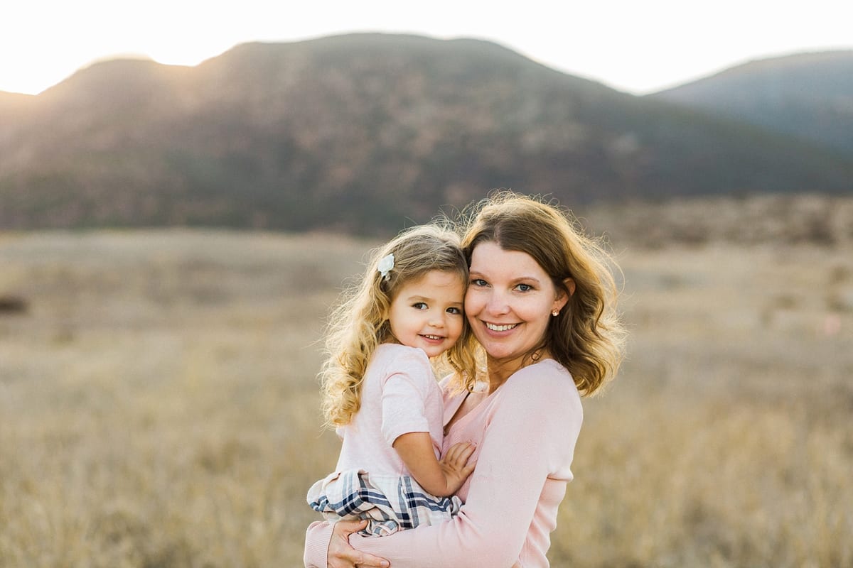 Mother holding her smiling daughter in a golden field