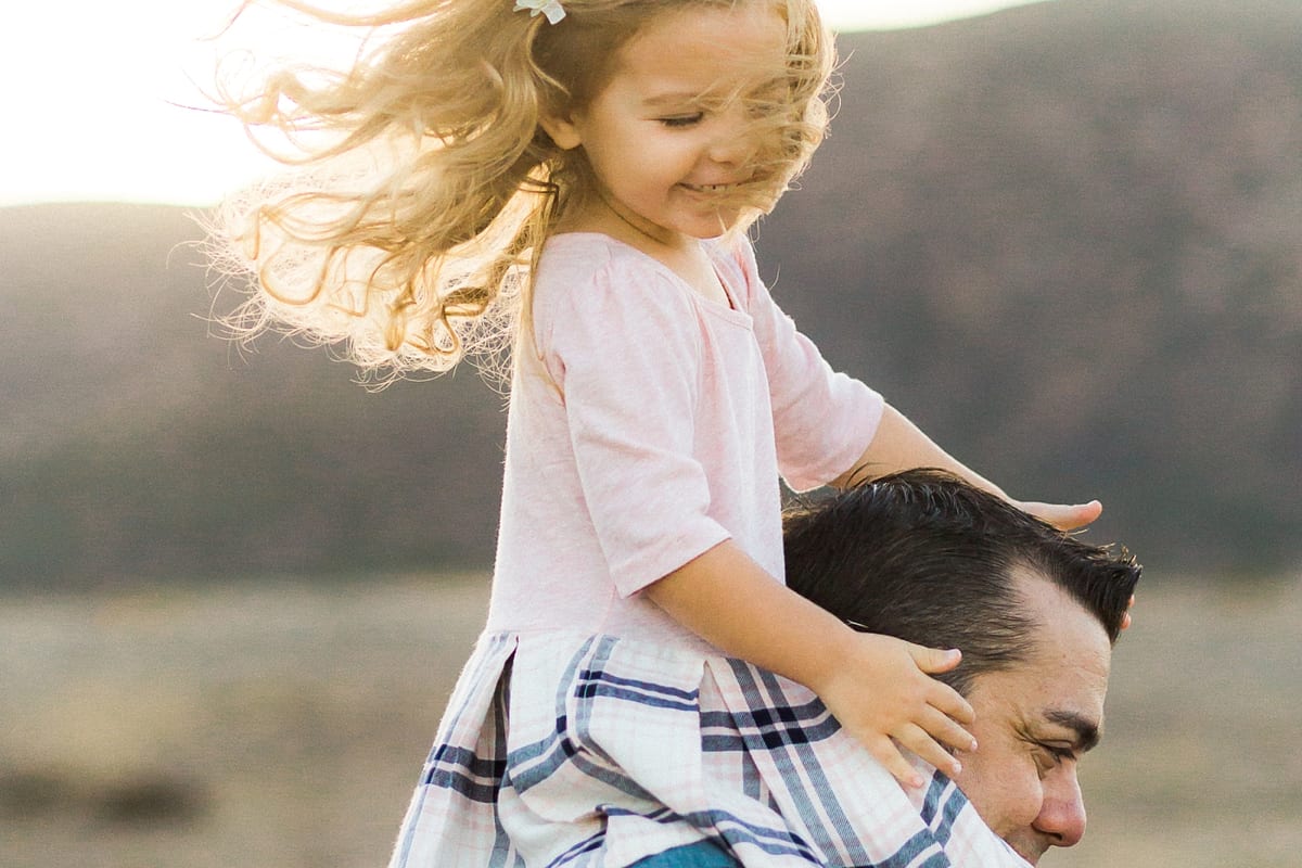Wind-blown girl riding on her father's shoulders