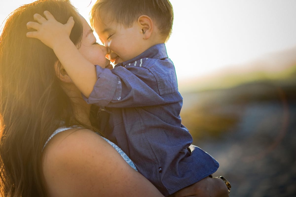 Mother and toddler son touching noses in warm evening light