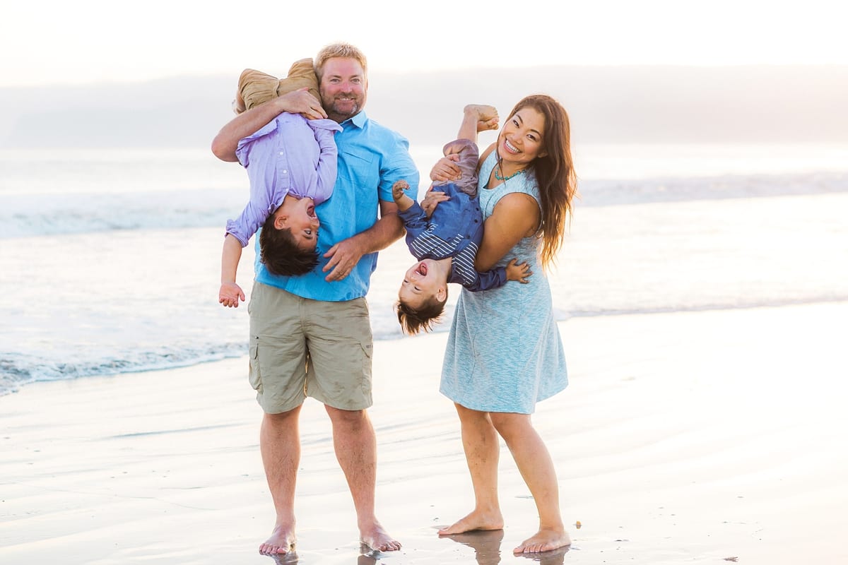 Parents holding their two sons upside down on the beach