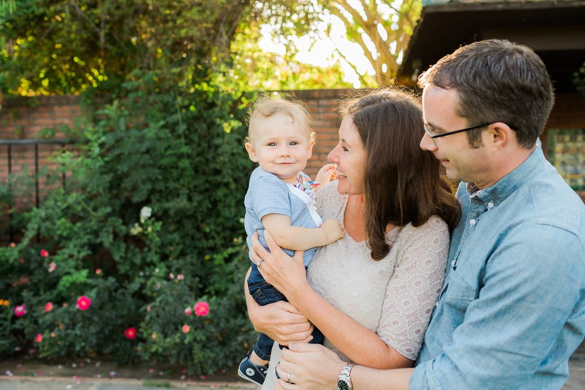 Mother and father holding their smiling baby son in a garden