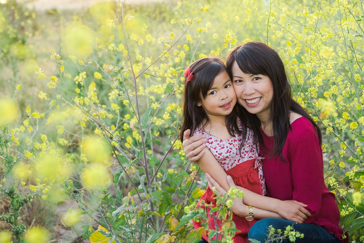 Smiling mother hugging her daughter in a field of yellow flowers