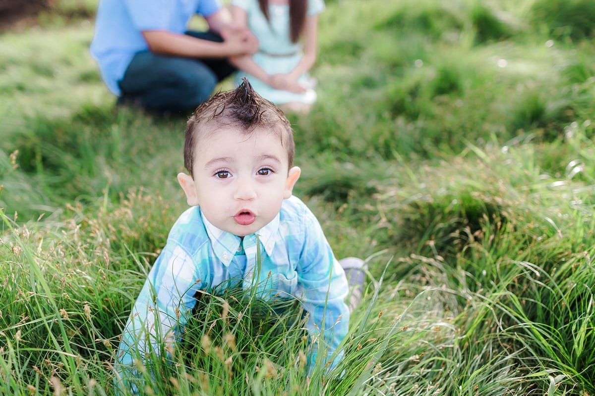 Baby boy with a spiky hairstyle crawling through tall grass