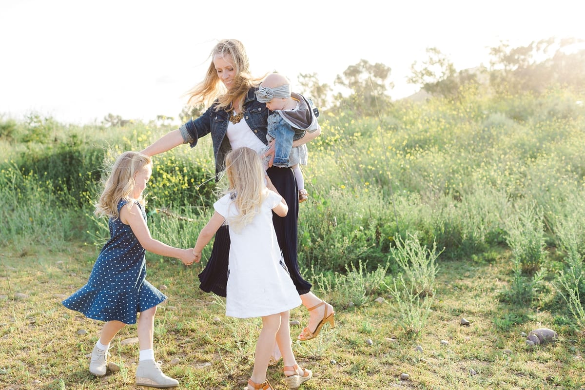 Mother dancing in a circle with her daughters in a wildflower meadow