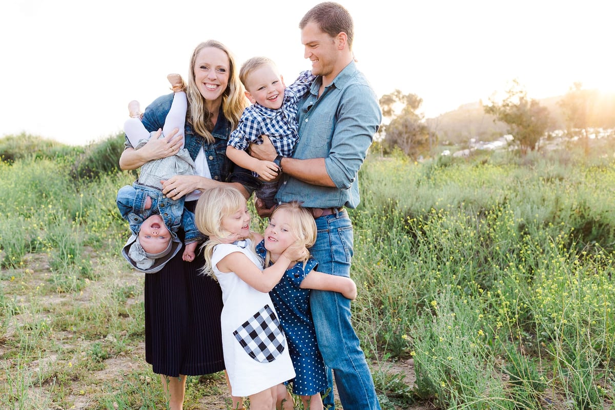 Parents laughing as they hug and tickle their four children
