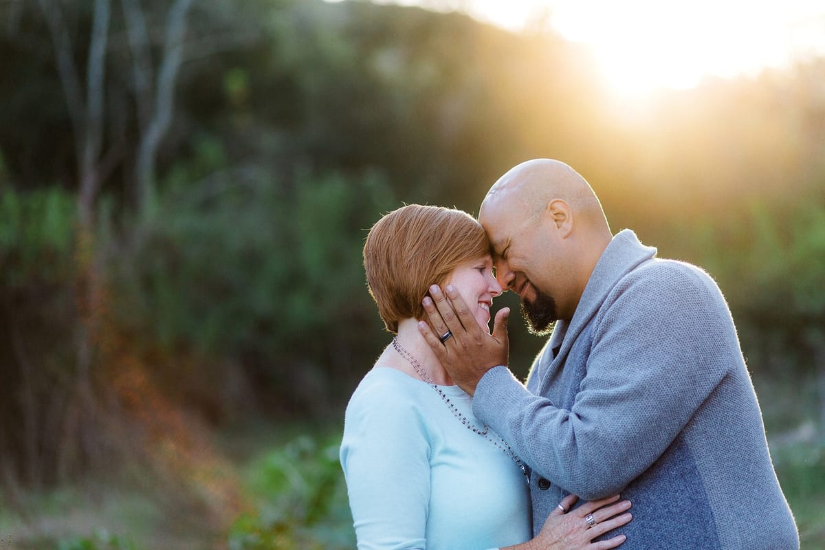 Couple leaning their foreheads together in soft evening light