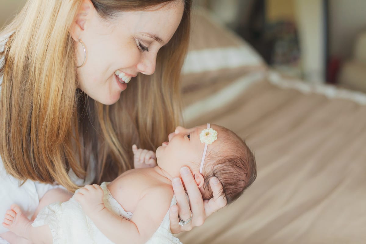 Mother smiling at the newborn daughter cradled in her hands