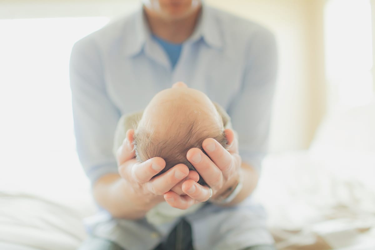 Father cradling his newborn's head in his hands