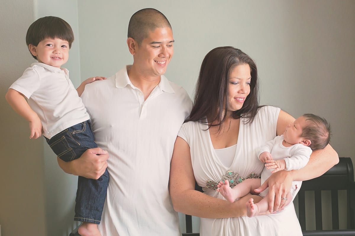Parents holding their toddler son and newborn baby at home