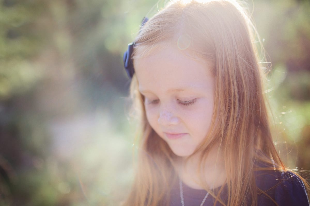 Red-haired girl looking down in soft backlight