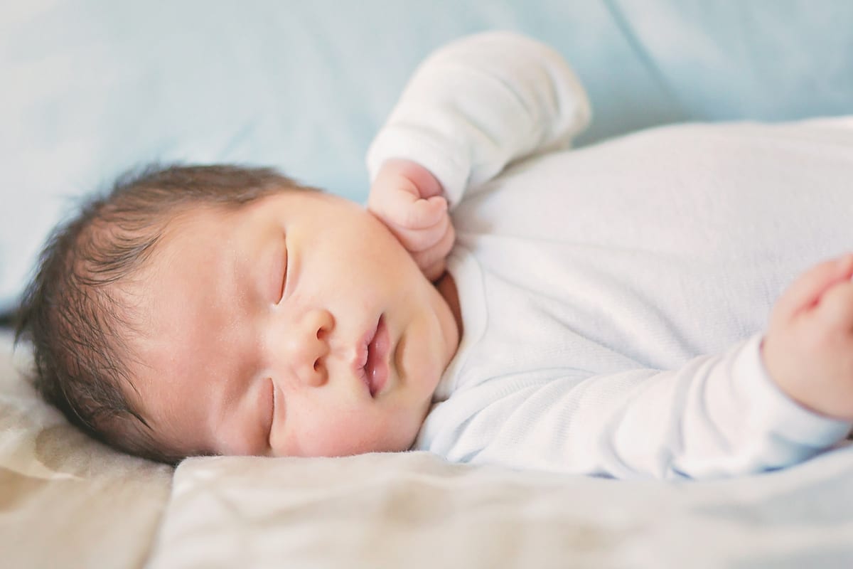 Newborn sleeping on patterned bedding