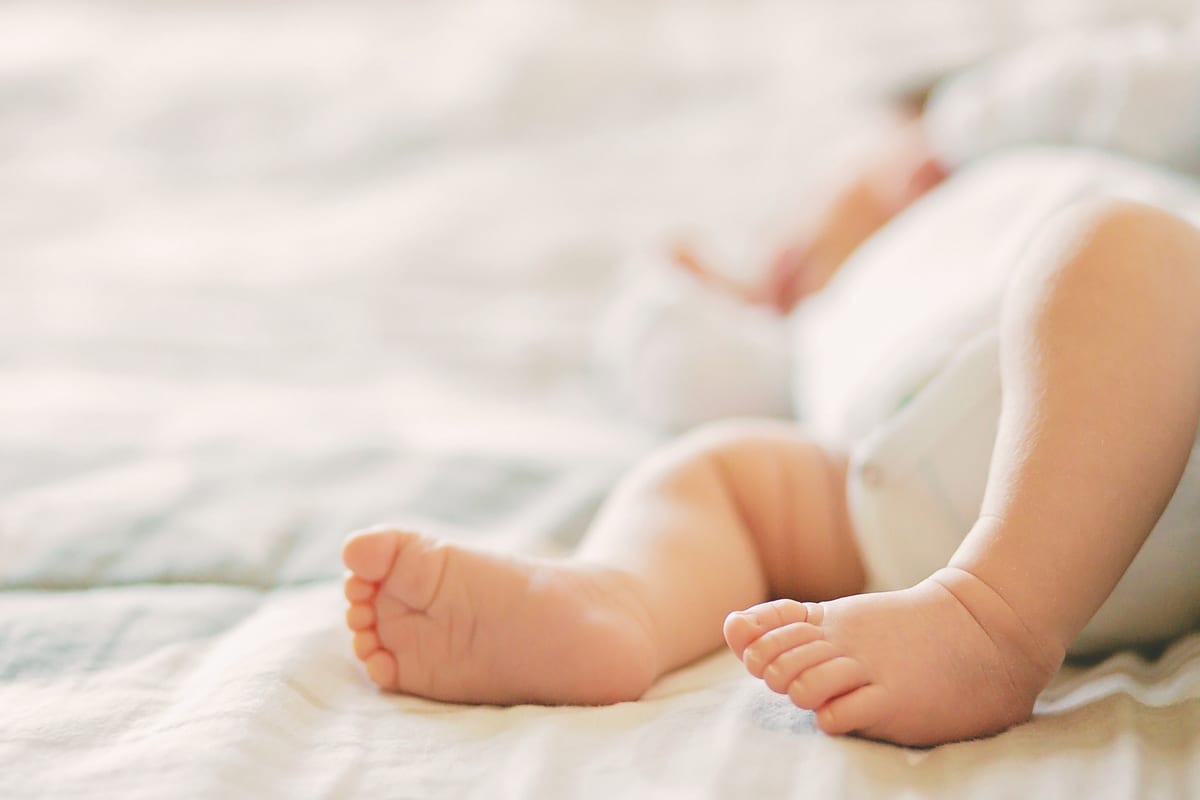 Close-up of a newborn's tiny feet on the bed