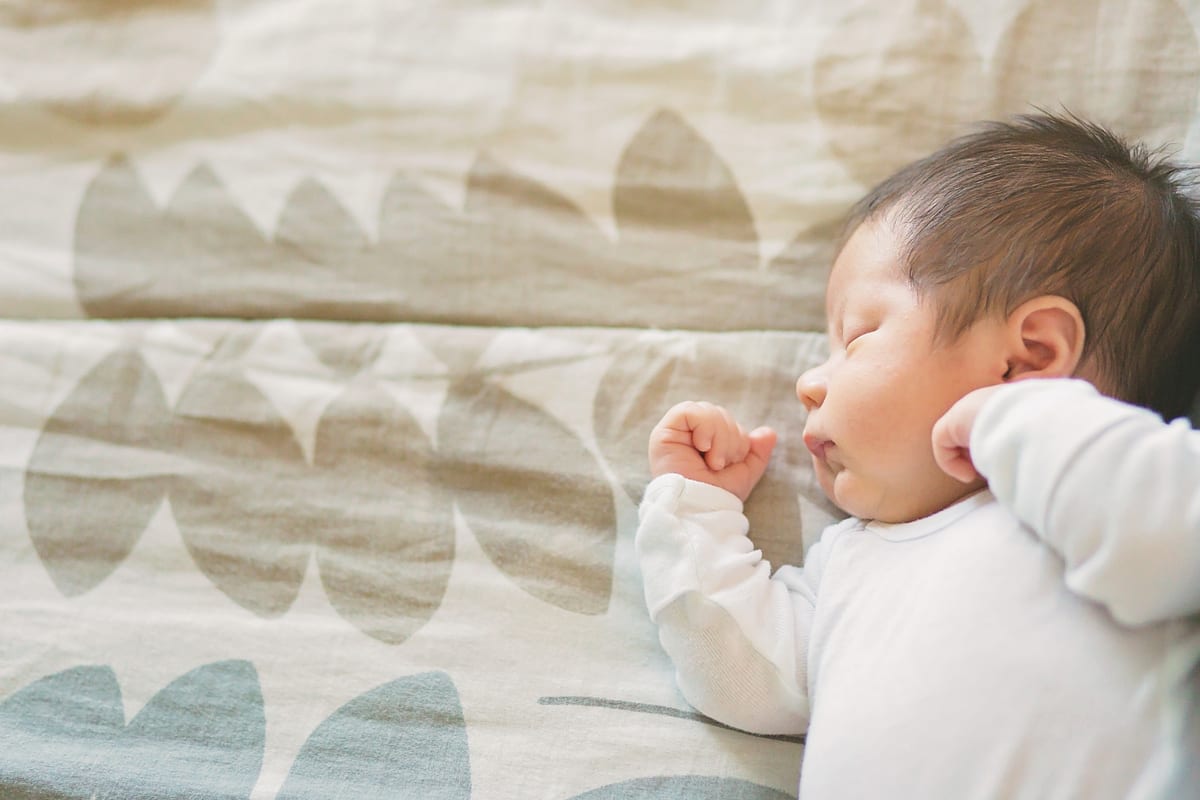 Sleeping newborn in profile with a hand tucked by his face
