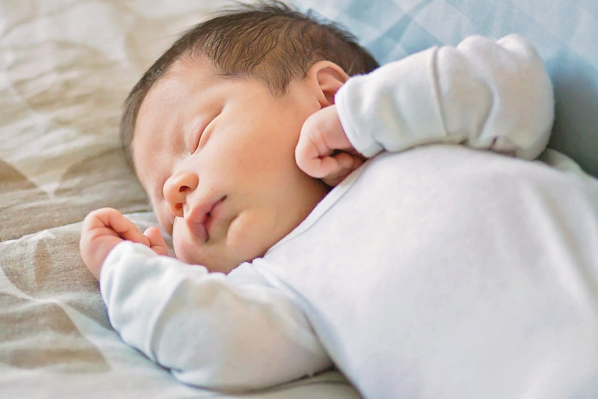 Close-up of a sleeping newborn's face and tiny fist