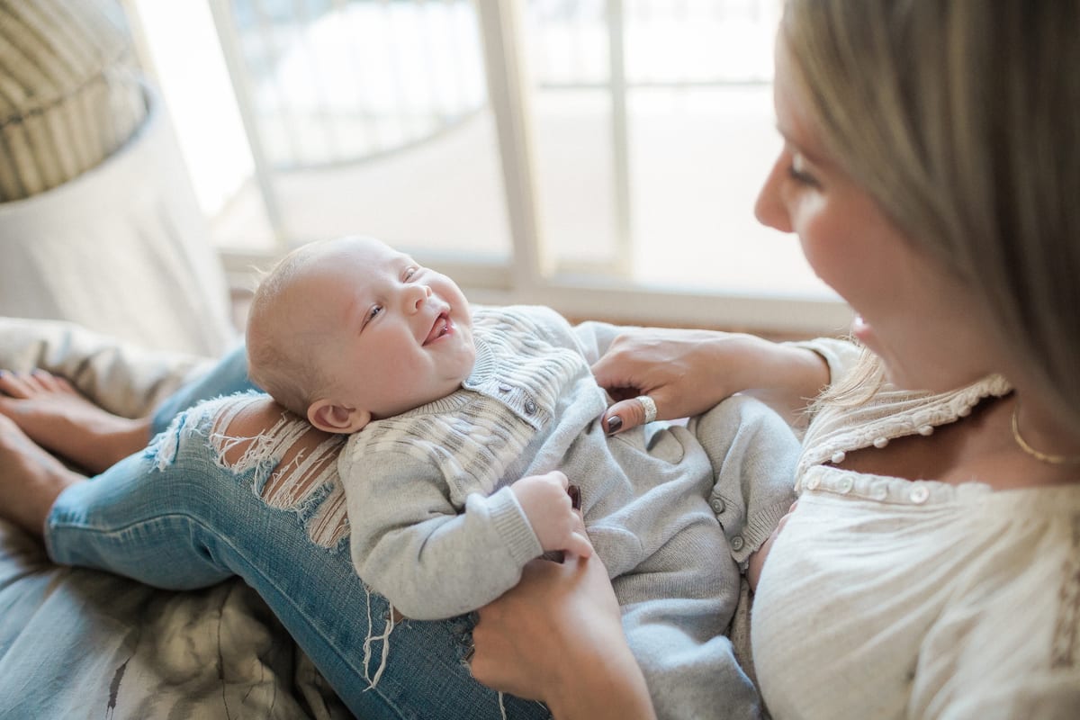Mother smiling down at her baby son lying on her lap