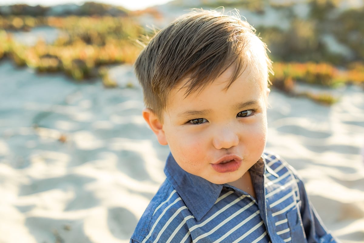 Close-up of a toddler boy puckering his lips in the sand dunes