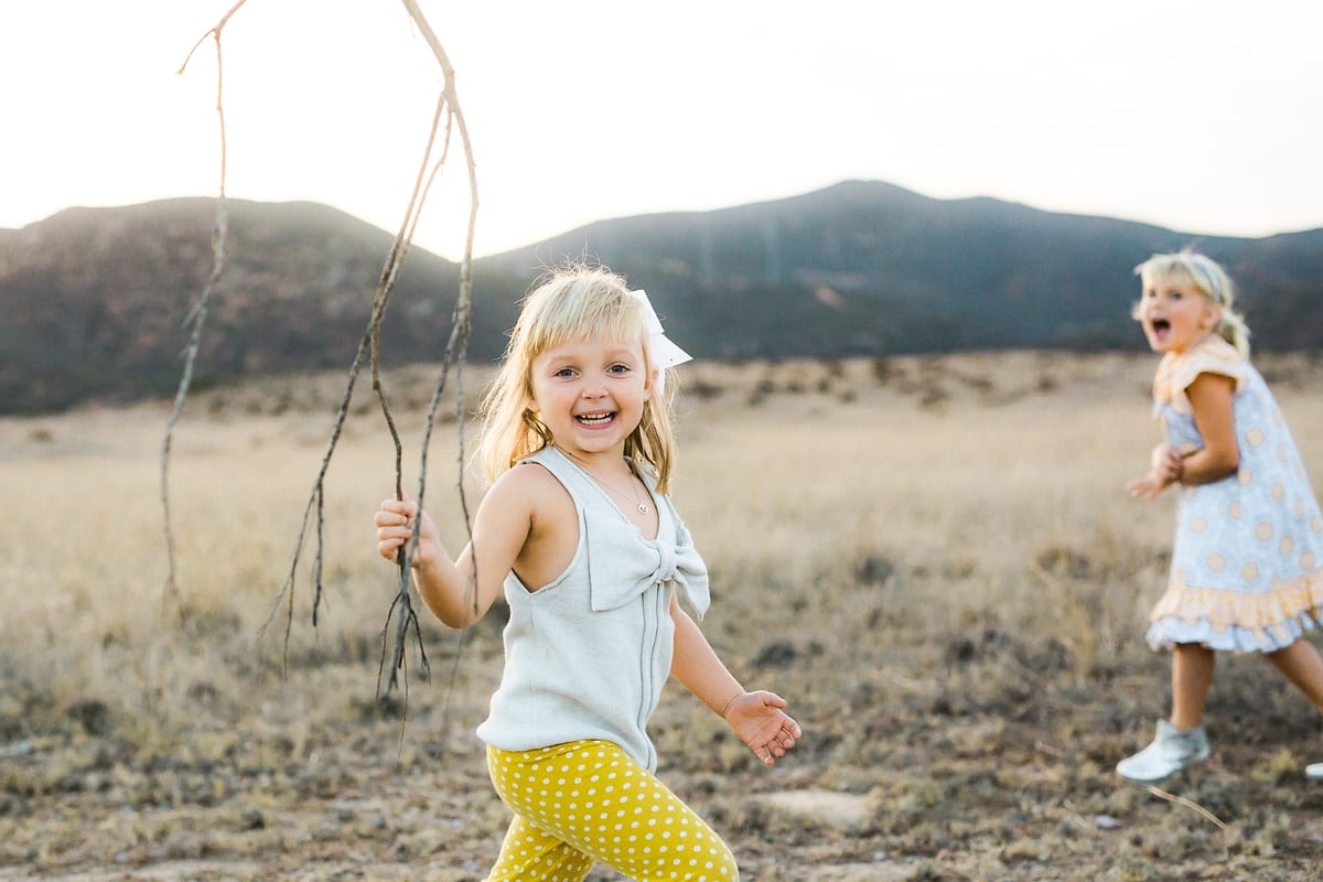 Two giggling sisters running through a golden field