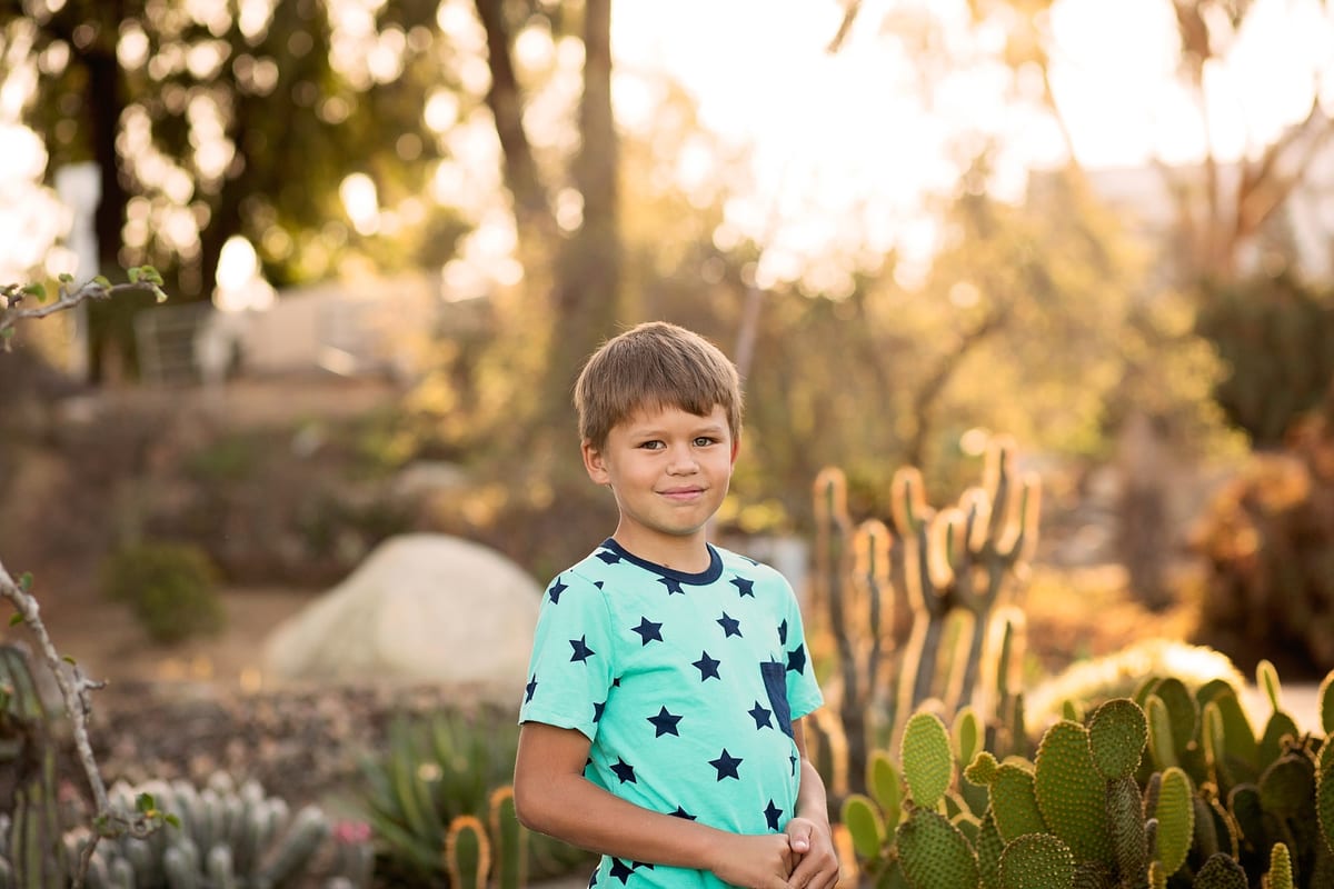 Boy in a star T-shirt standing in a cactus garden at sunset