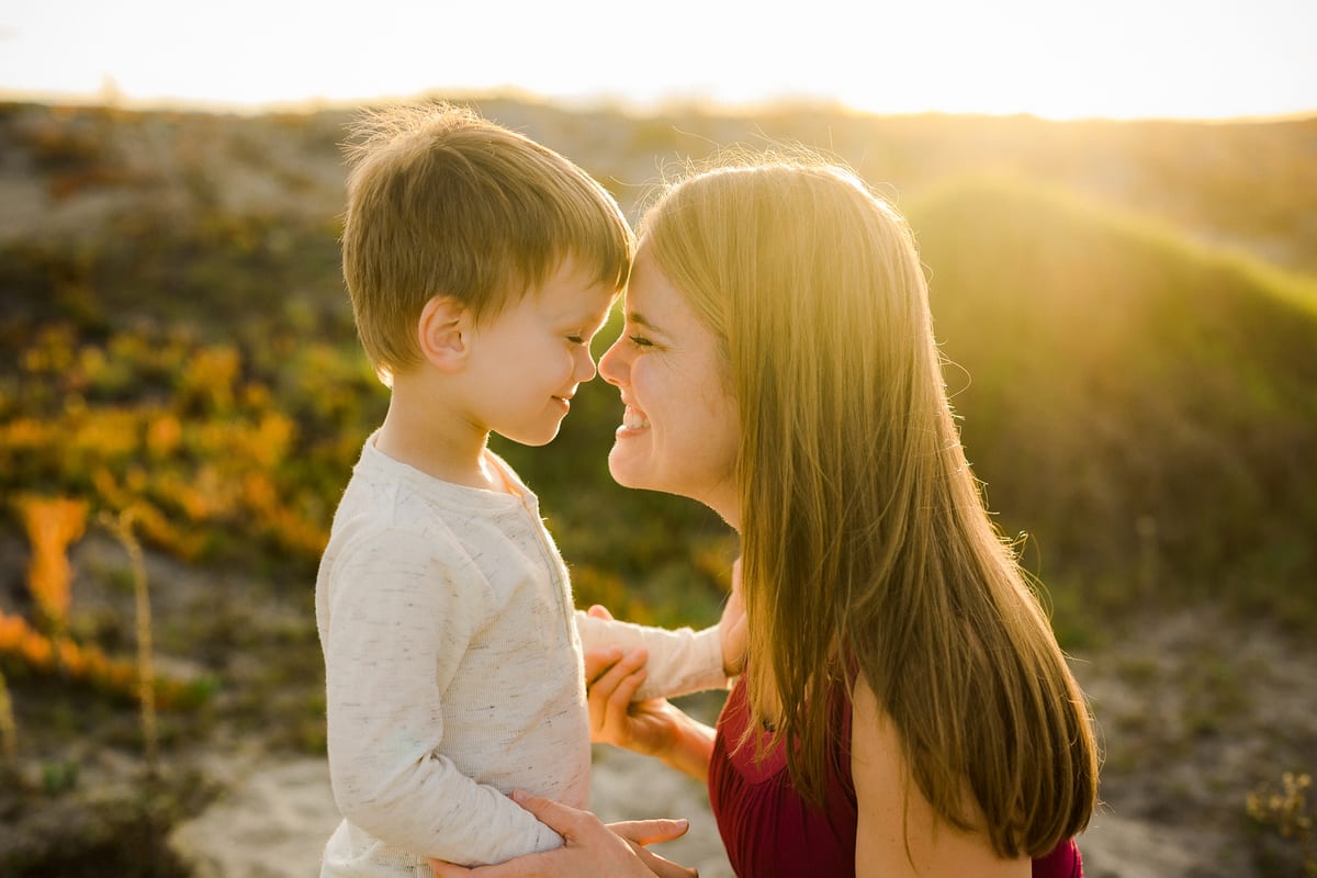Young son and mother touching noses in warm sunset light